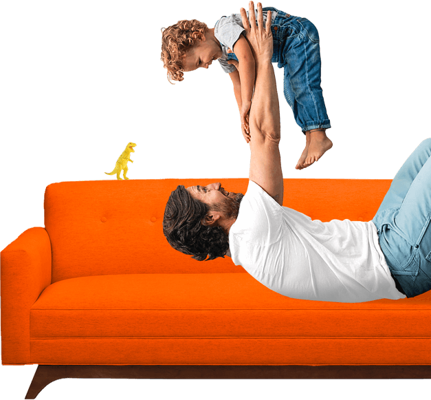 Man on a bright-colored sofa lifting a young child overhead